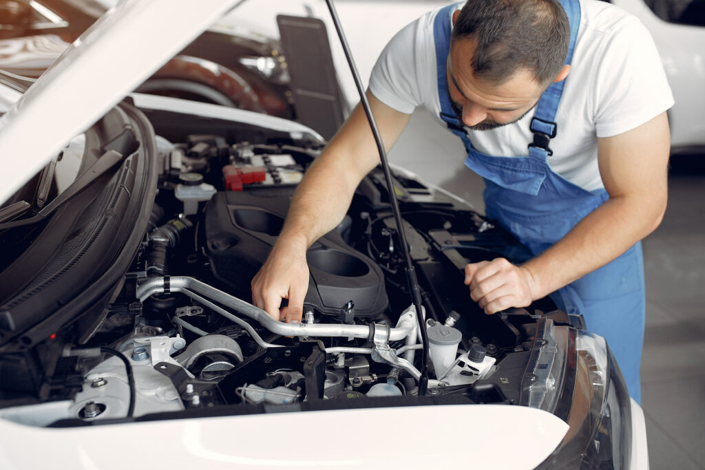Wrker in a car salon. Expert checks the car. Man in a blue uniform.